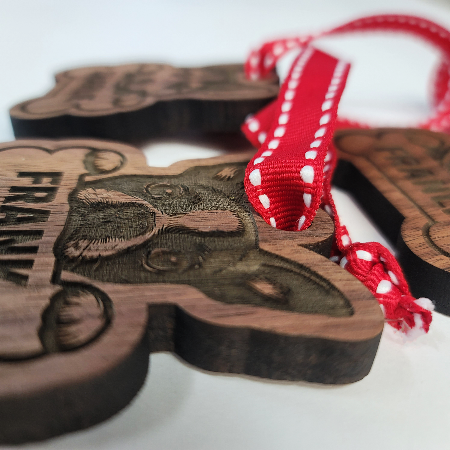 Wooden ornament with engraved design and red ribbon on a white background