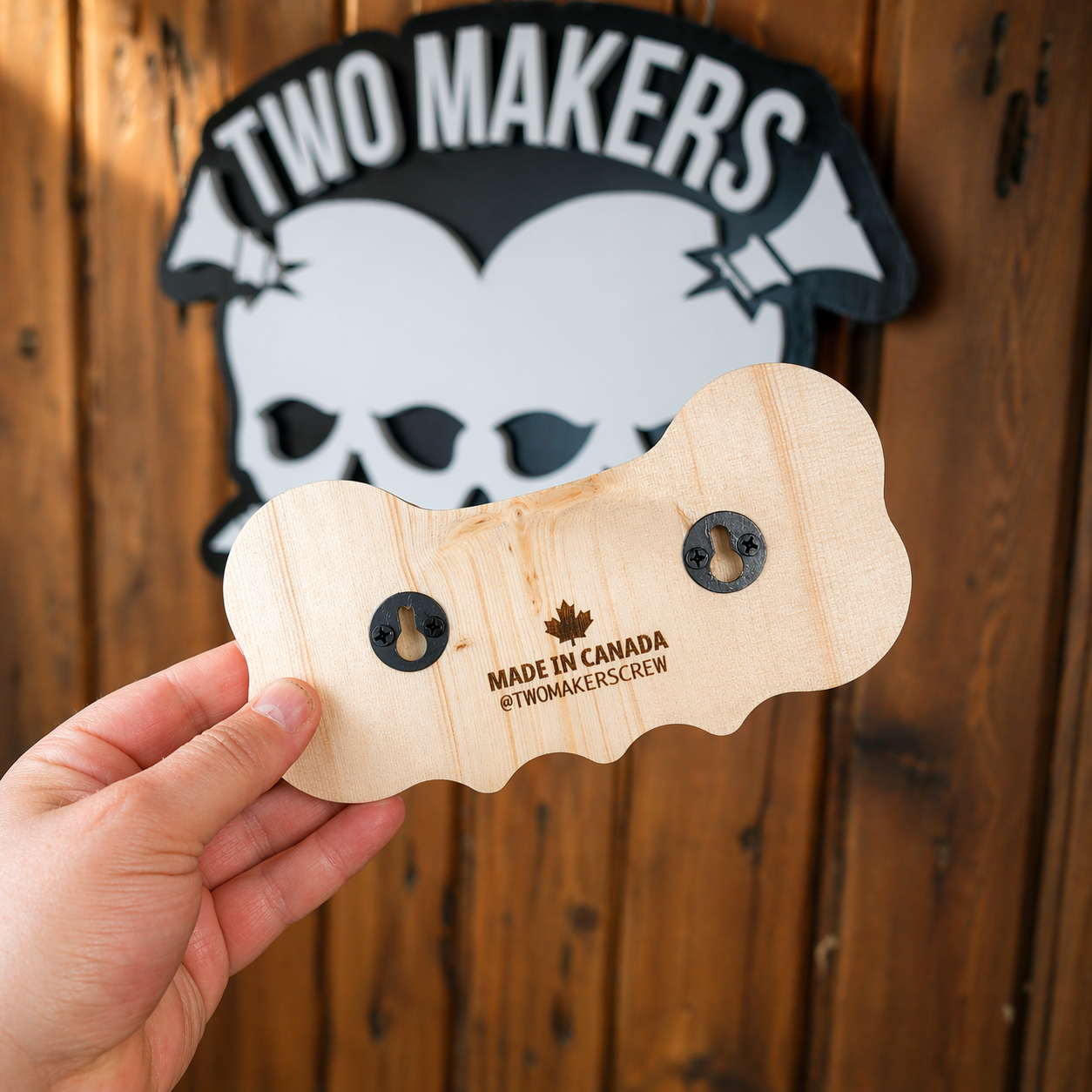 Wooden product with 'Made in Canada' text held by a hand, against a wooden background with 'Two Makers' logo.