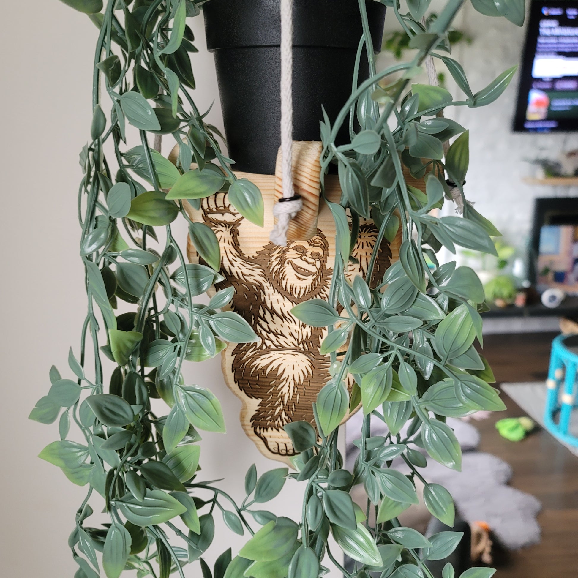 Decorative wreath with green leaves and a wooden bear ornament on a white surface.
