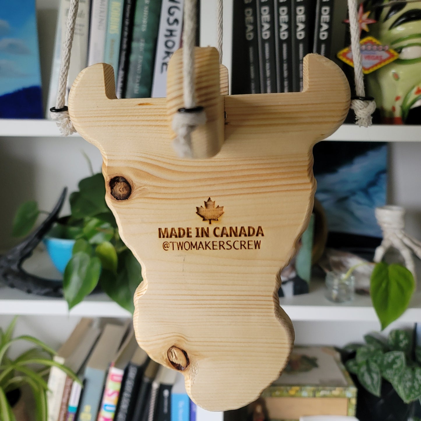 Wooden plant holder with 'Made in Canada' text on a blurred bookshelf background