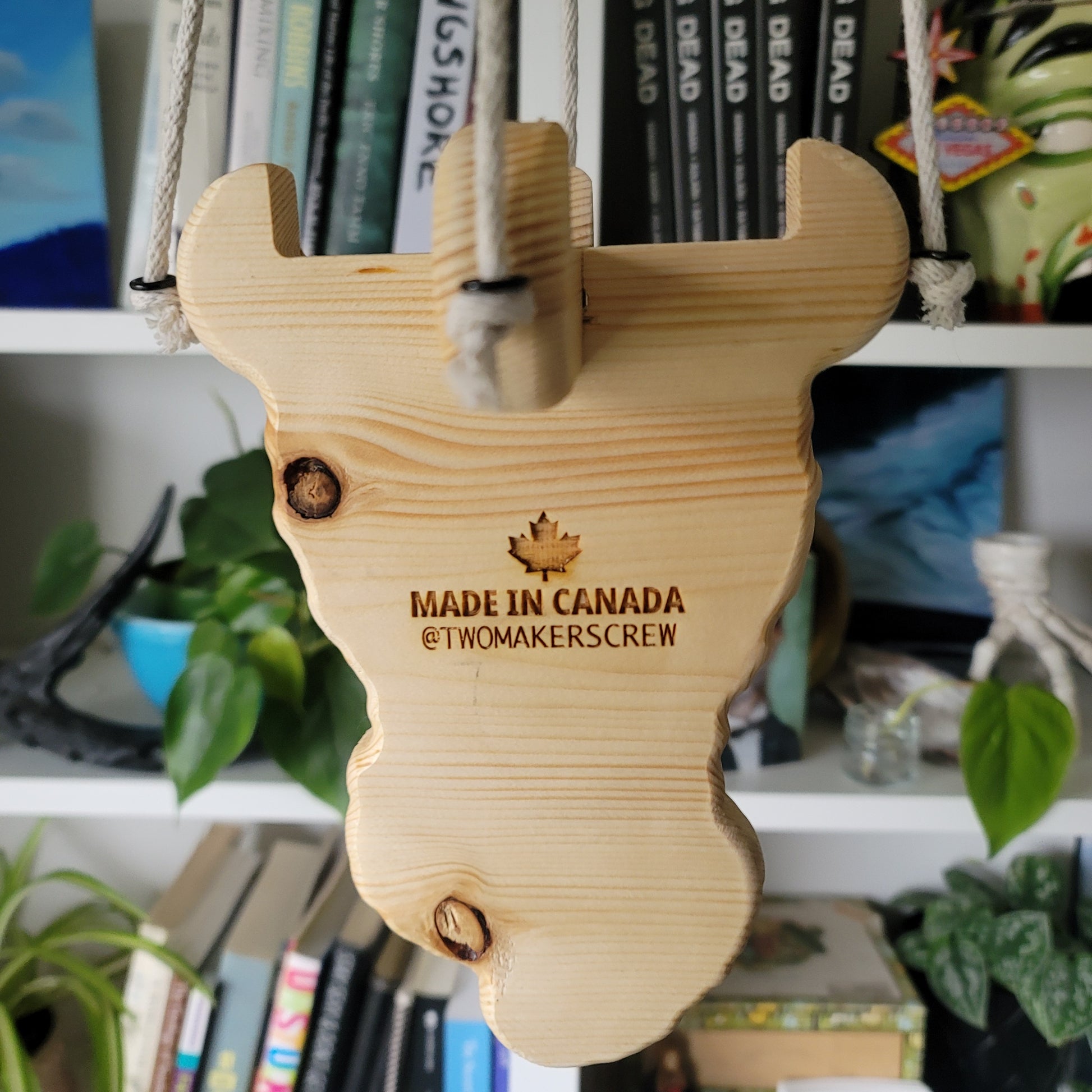 Wooden plant holder with 'Made in Canada' text on a blurred bookshelf background